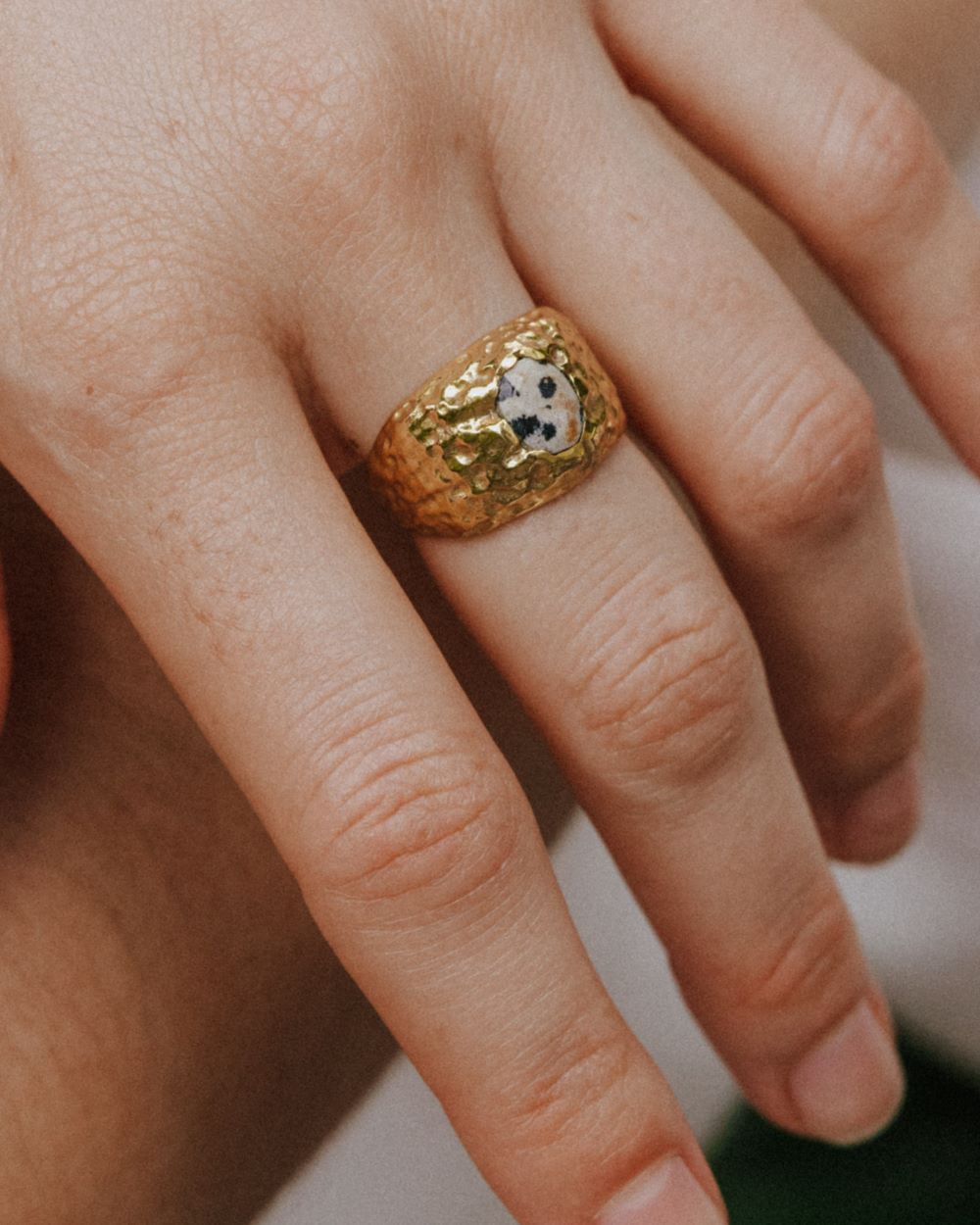 Primer plano de la mano de la modelo con el anillo bañado en oro de 18k con piedra semipreciosa Jaspe Dálmata de Isla Vurma