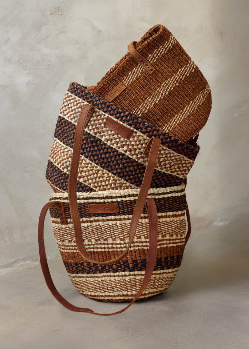 Bodegón de bolsos de sisal artesanales de Isla Vurma en tonos tierra y rayas étnicas, con asas de cuero - colección de bolsos sostenibles estilo boho para verano