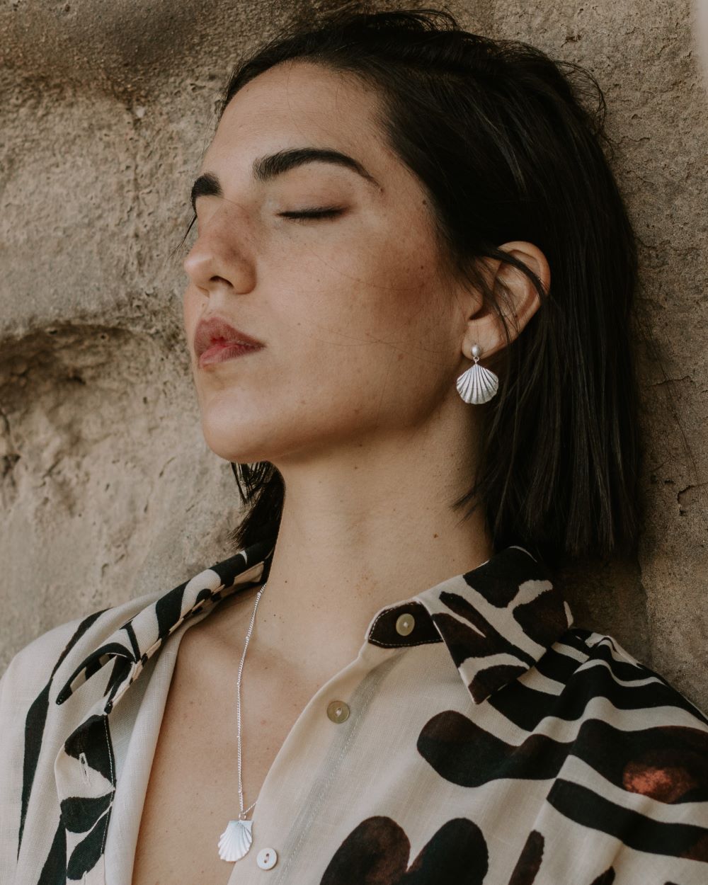 Modelo que con conjunto de collar y pendientes en forma de concha de mar en acabado plateado