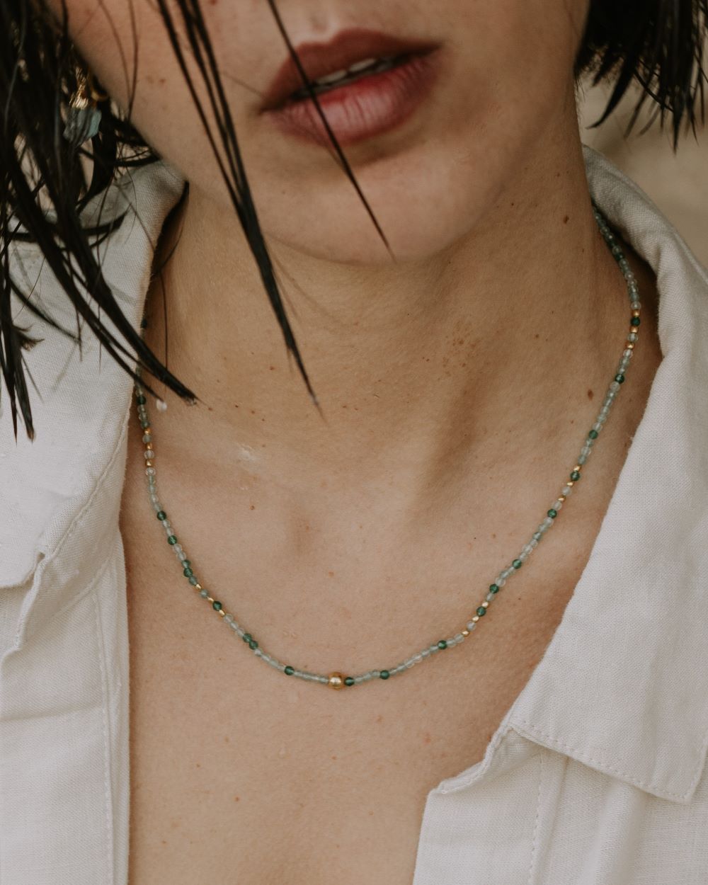 Modelo con collar con la piedra en tonos verdes