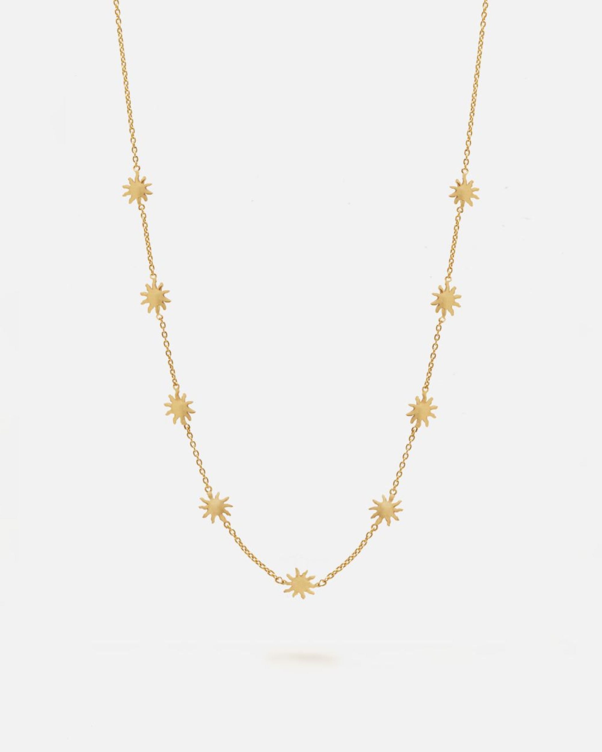 Collar dorado de cadena fina decorado con pequeños colgantes en forma de estrella de ocho puntas distribuidos de manera uniforme