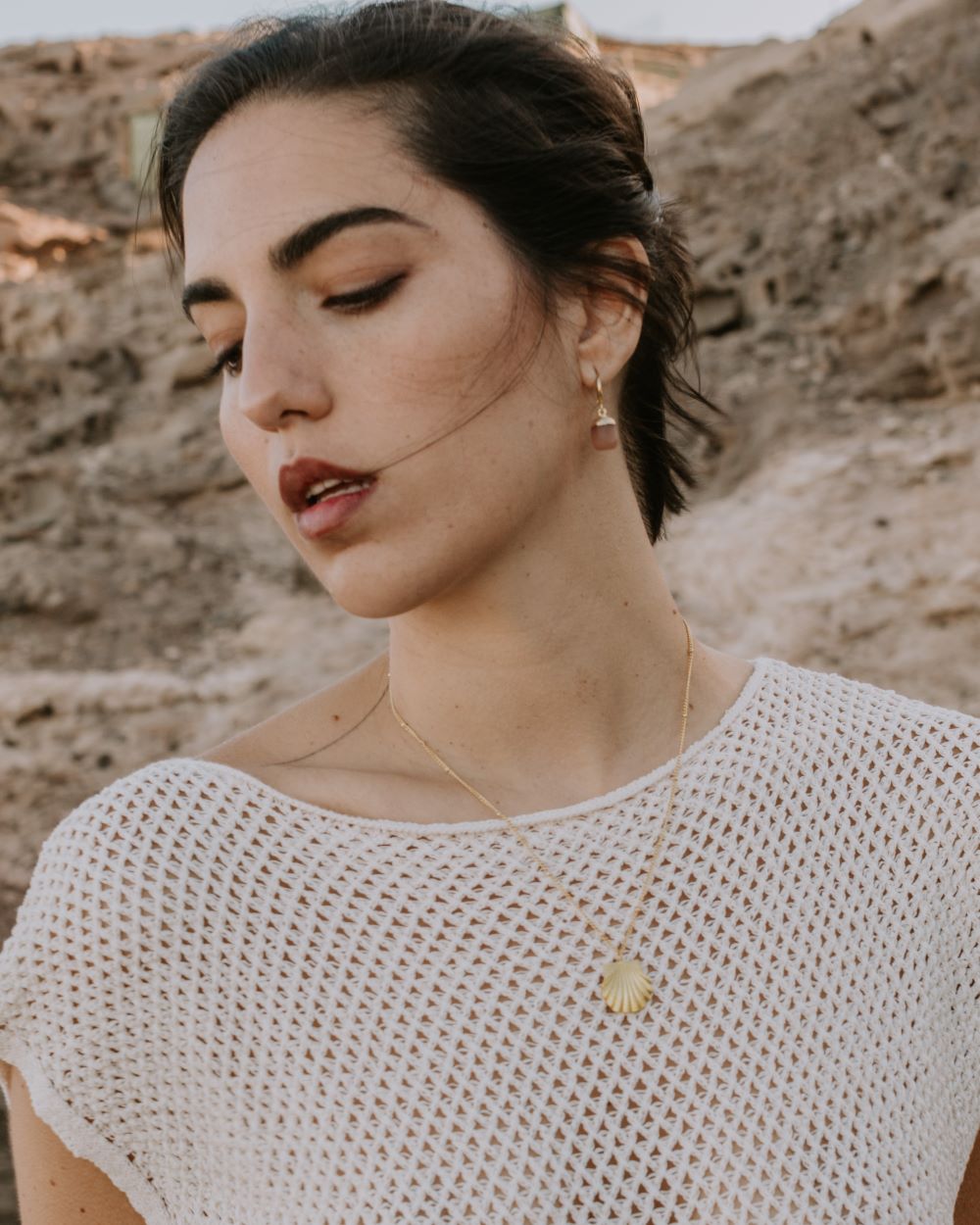 Modelo con collar en forma de concha dorada y pendientes con piedra natural
