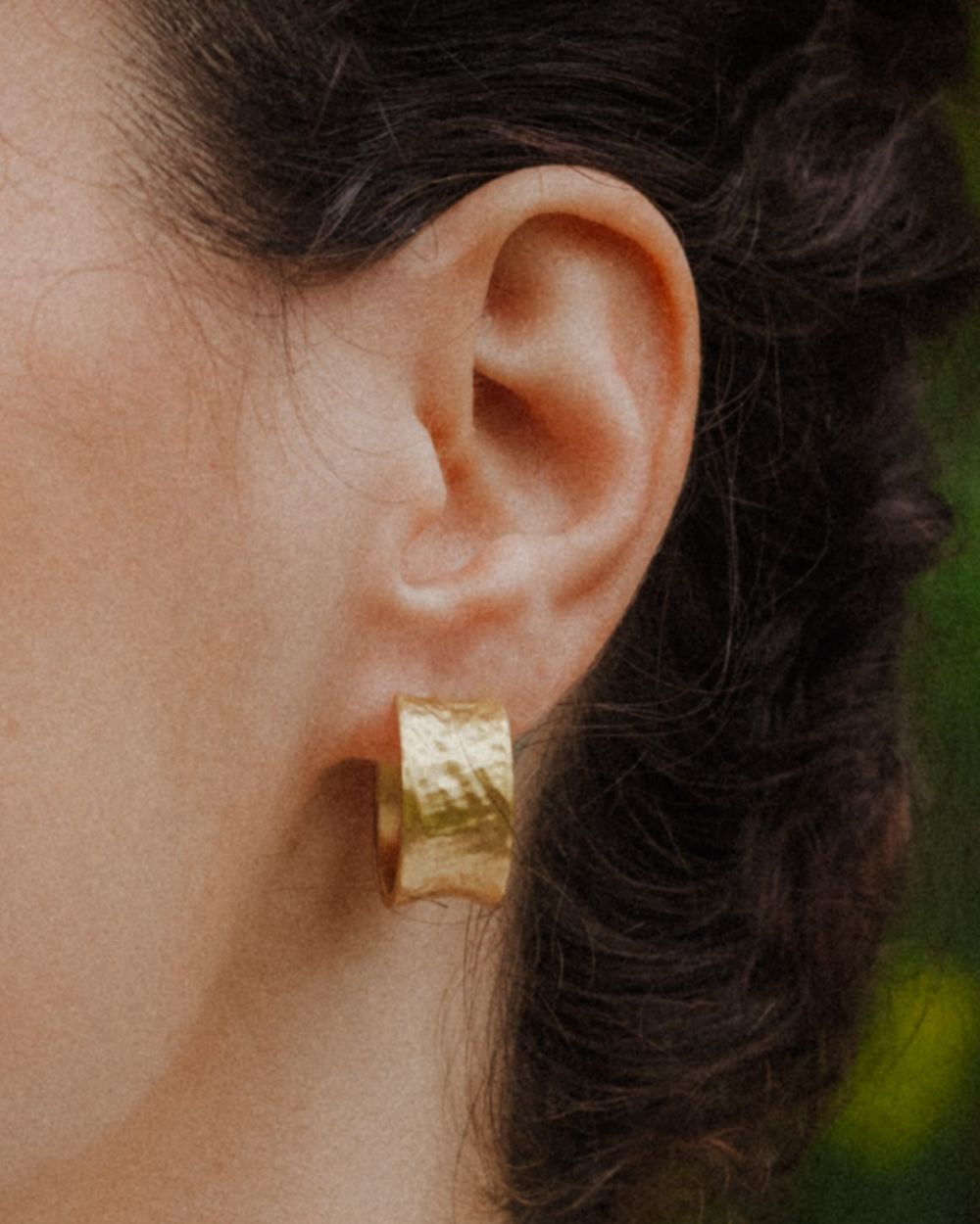 Primer plano de la modelo con los pendientes bañados en oro de 18 quilates ondulados y cierre mariposa de Isla Vurma