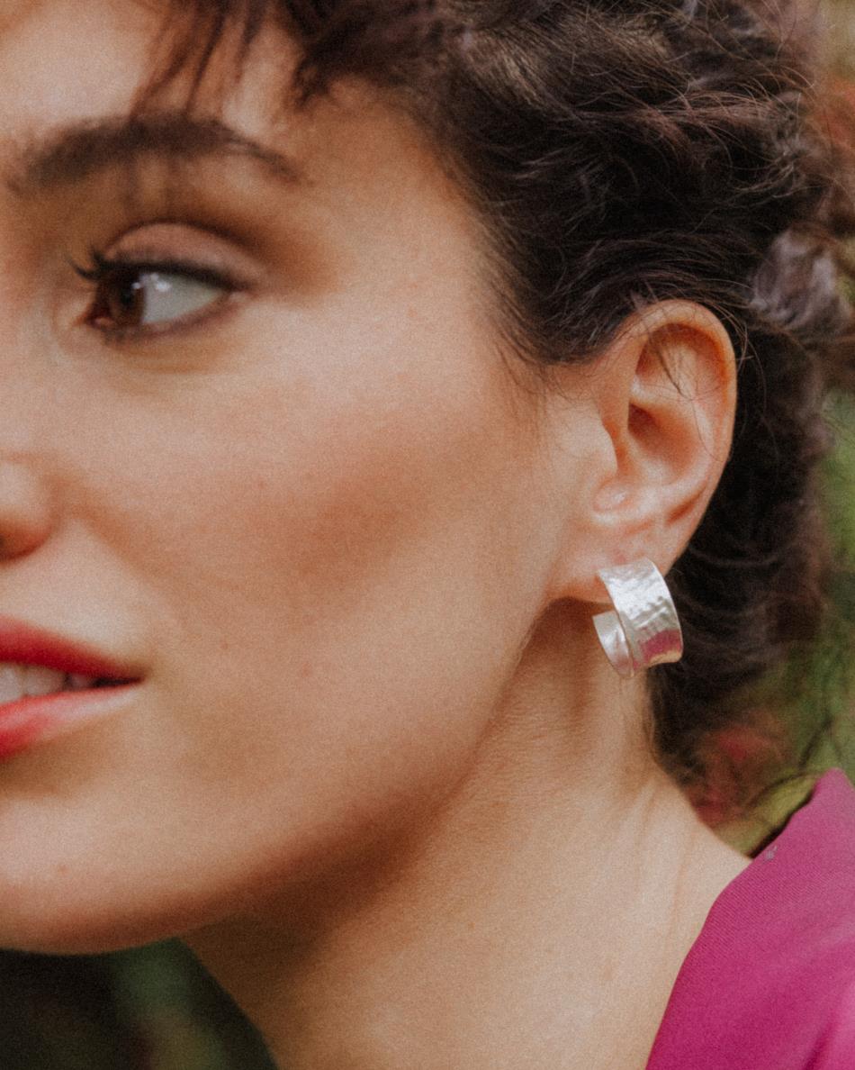 Primer plano de la modelo con los pendientes bañados en plata 925 ondulados y cierre mariposa de Isla Vurma