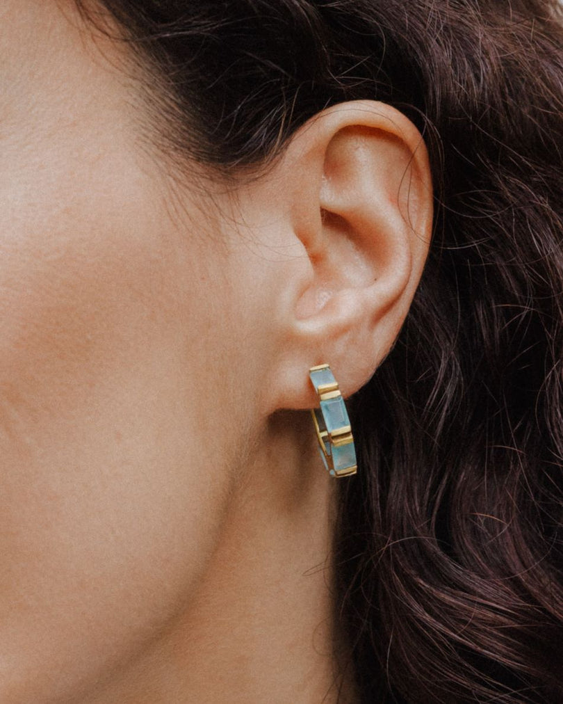 Pendiente Magnolia de aro dorado con piedras Aqua Calcedonia lucido en la oreja de la modelo