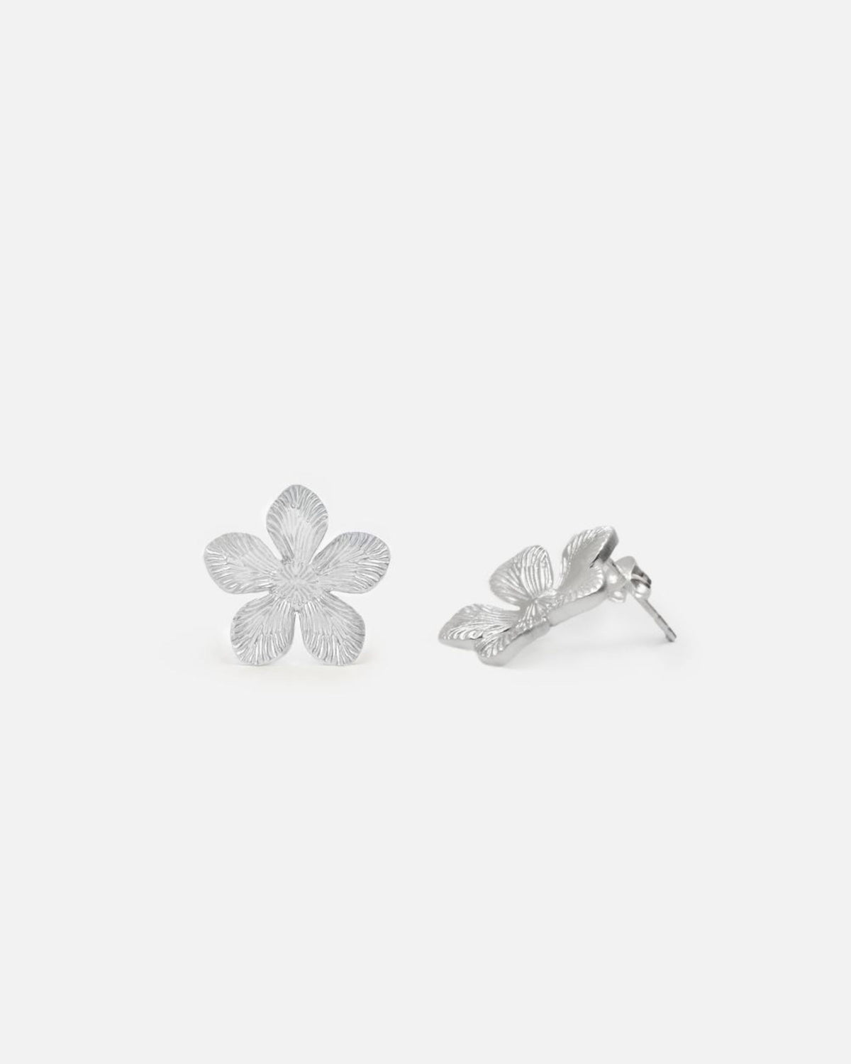 Pendientes plateados con forma de flor de cinco pétalos, con textura grabada.