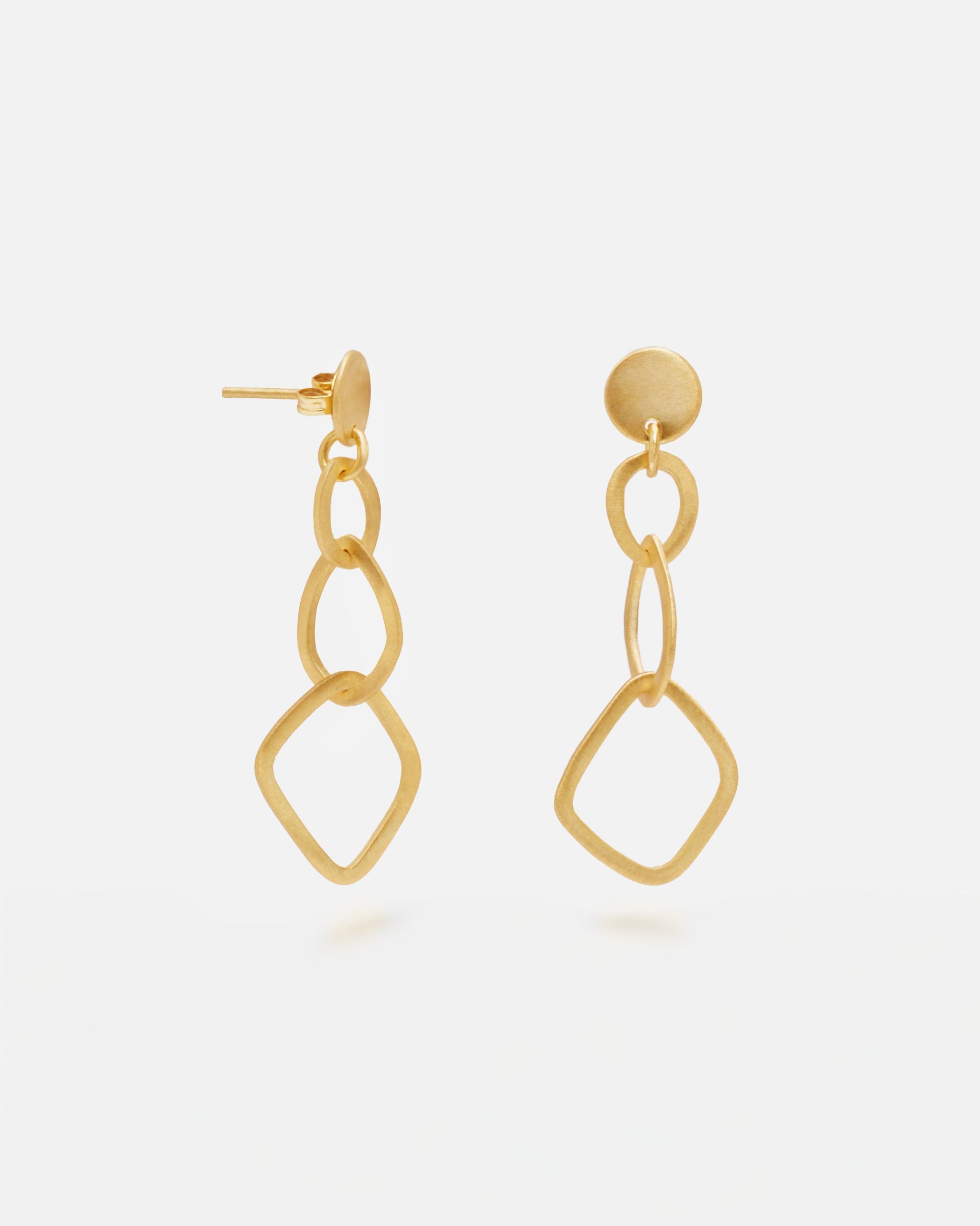 Primer plano de los pendientes geométricos largos bañados en oro de 18k de Isla Vurma