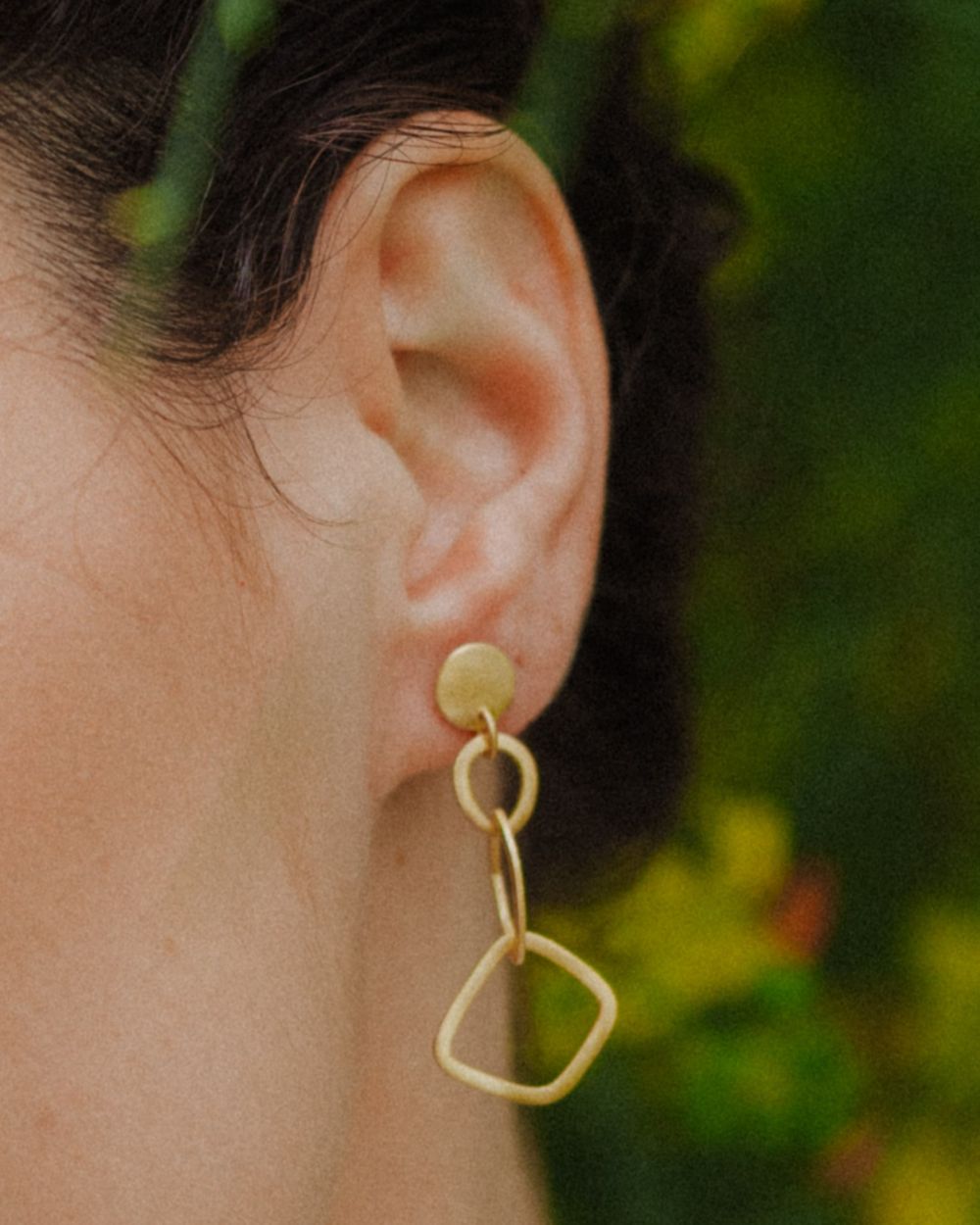 Primer plano de la modelo con los pendientes geométricos largos bañados en oro de 18k de Isla Vurma