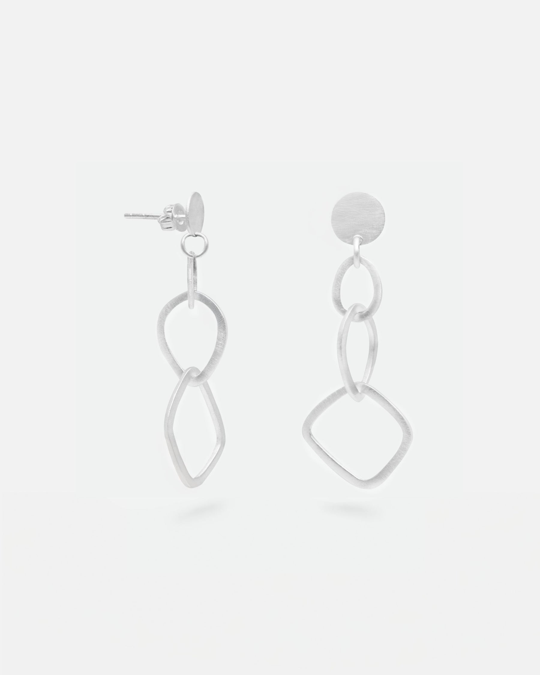 Primer plano de los pendientes geométricos largos bañados en plata 925 de Isla Vurma