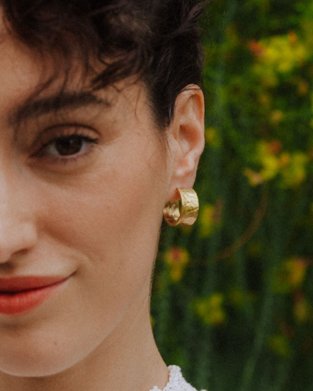 Primer plano de la modelo con los pendientes bañados en oro de 18 quilates ondulados abiertos y cierre mariposa de Isla Vurma