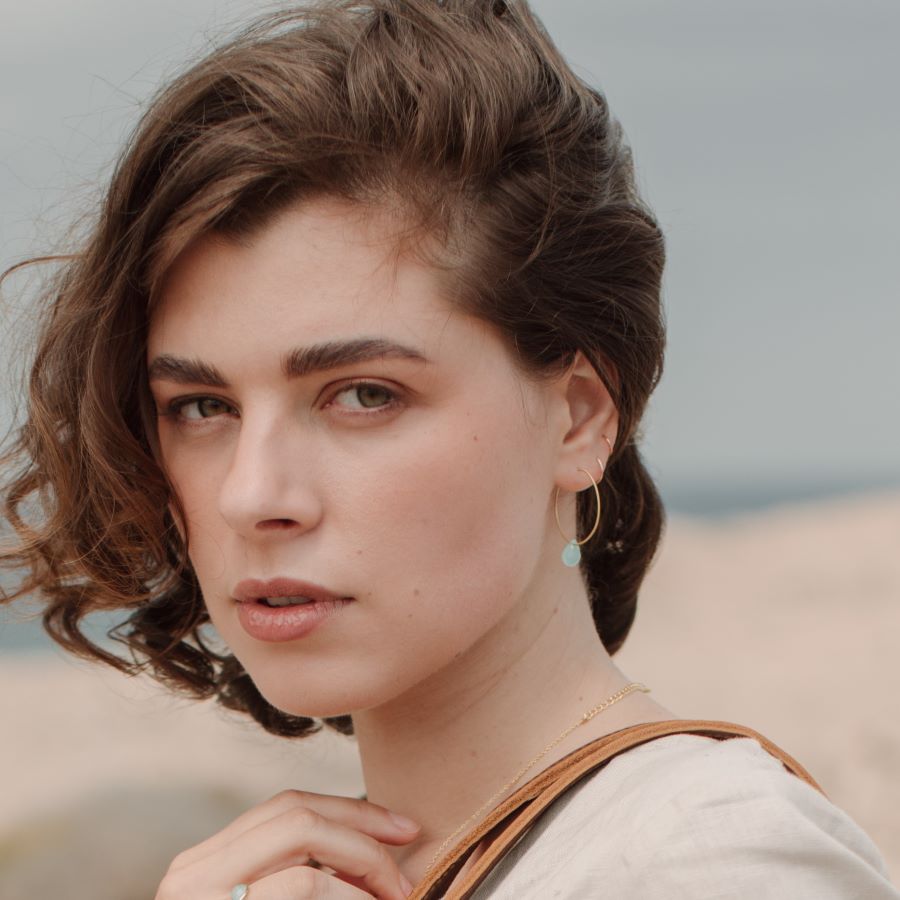 Primer plano de la modelo luciendo los pendientes bañados en Oro de 18 quilates con piedra semipreciosa Aqua Calcedonia en forma de gota