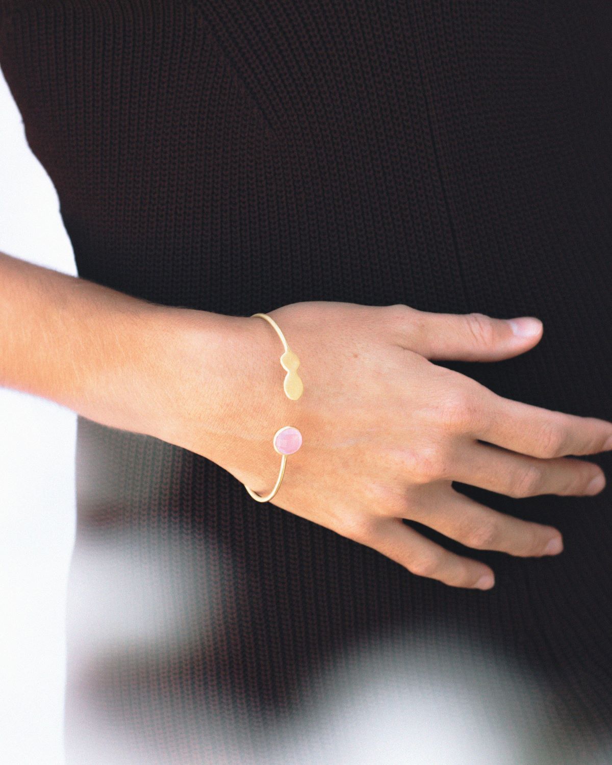 Primer plano del brazo de la modelo con el brazalete de latón bañado en oro de 18 quilates con una piedra semipreciosa en Cuarzo Rosa de Isla Vurma