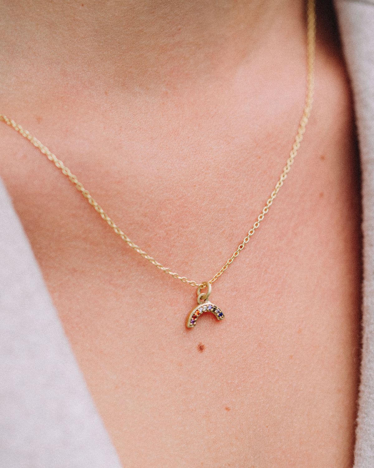 Modelo con collar dorado en forma de arcoiris con piedras semipreciosas incrutadas de Isla Vurma