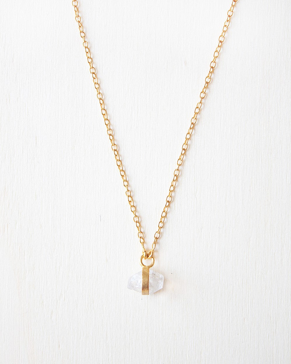 Primer plano del collar bañado en oro de 18 quilates, con piedra semipreciosa Piedra de Luna, sujetada por una pequeña pieza rectangular dorada de Isla Vurma