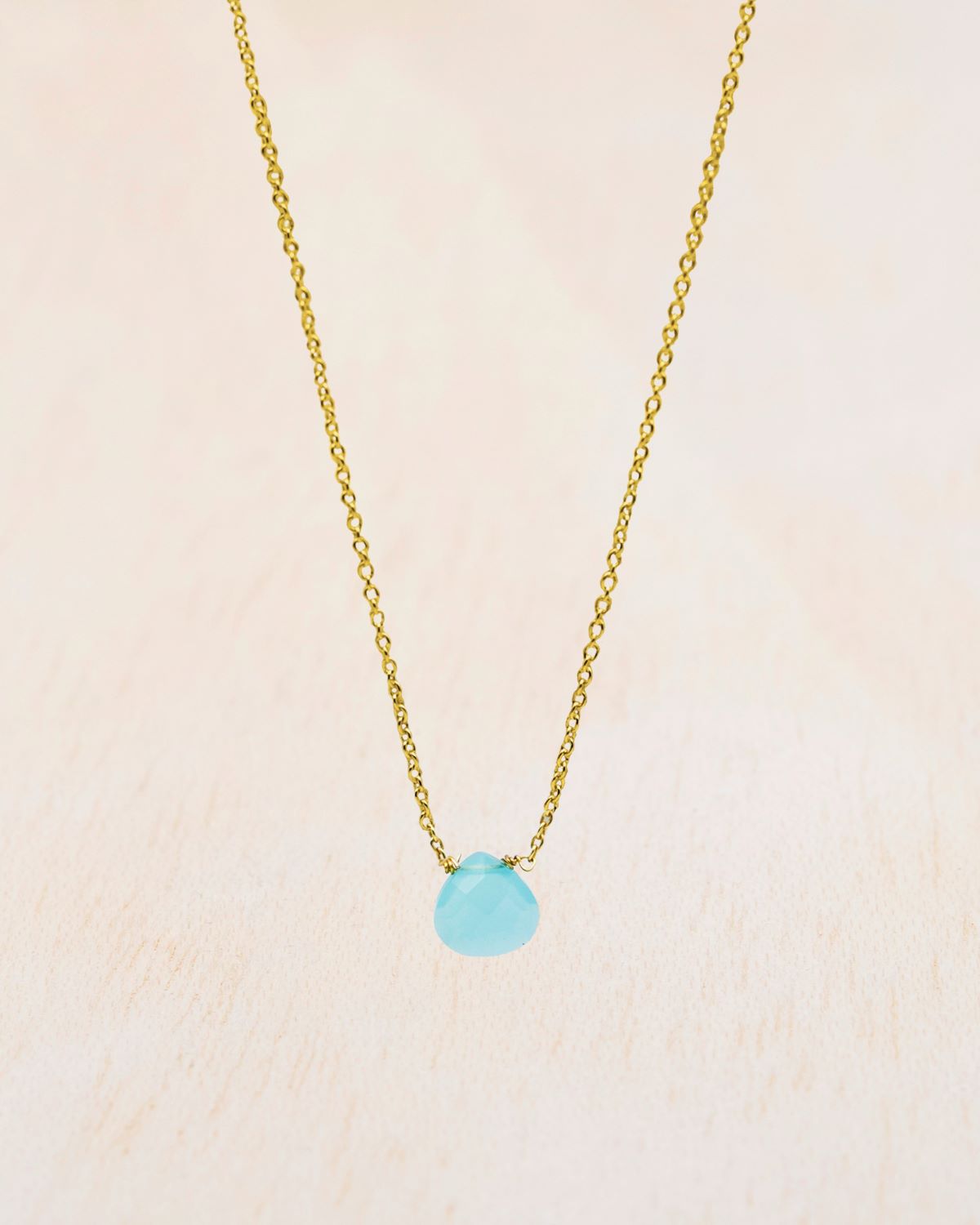 Primer plano del collar bañado en oro de 18 quilates con piedra tallada en Aqua Calcedonia de Isla Vurma