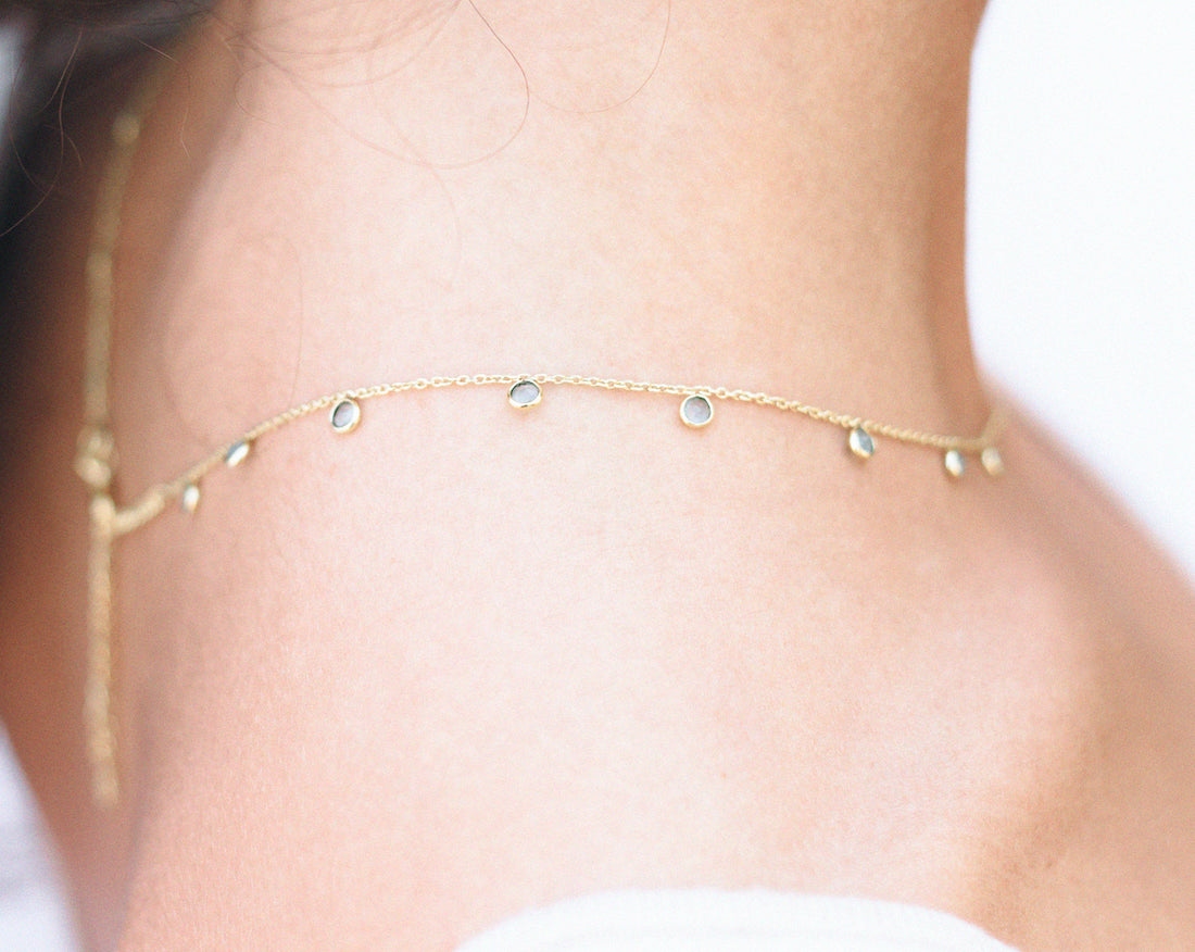 Collar bañado en oro de 18 quilates posado en cuello de modelo colgando hacia la espalda con piedra semipreciosa en Aqua Calcedonia