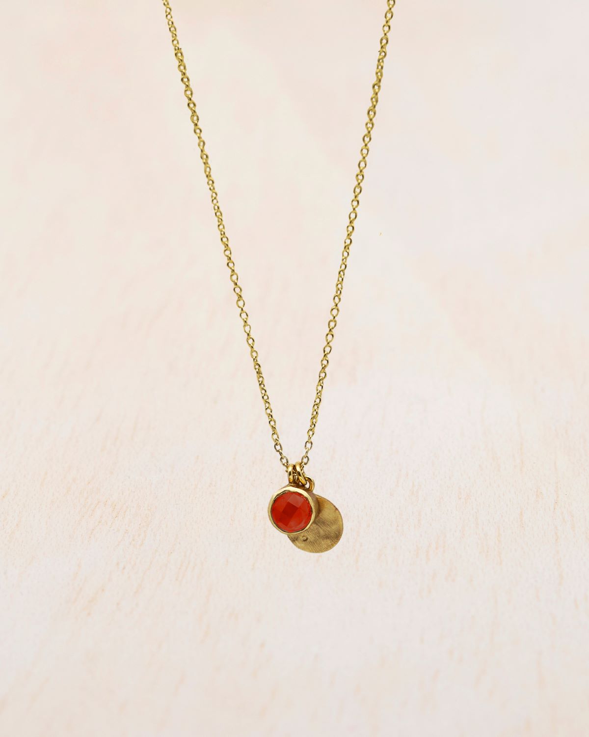 Primer plano sobre fondo blanco del collar bañado en oro con piedra semipreciosa en Cornalina de Isla Vurma