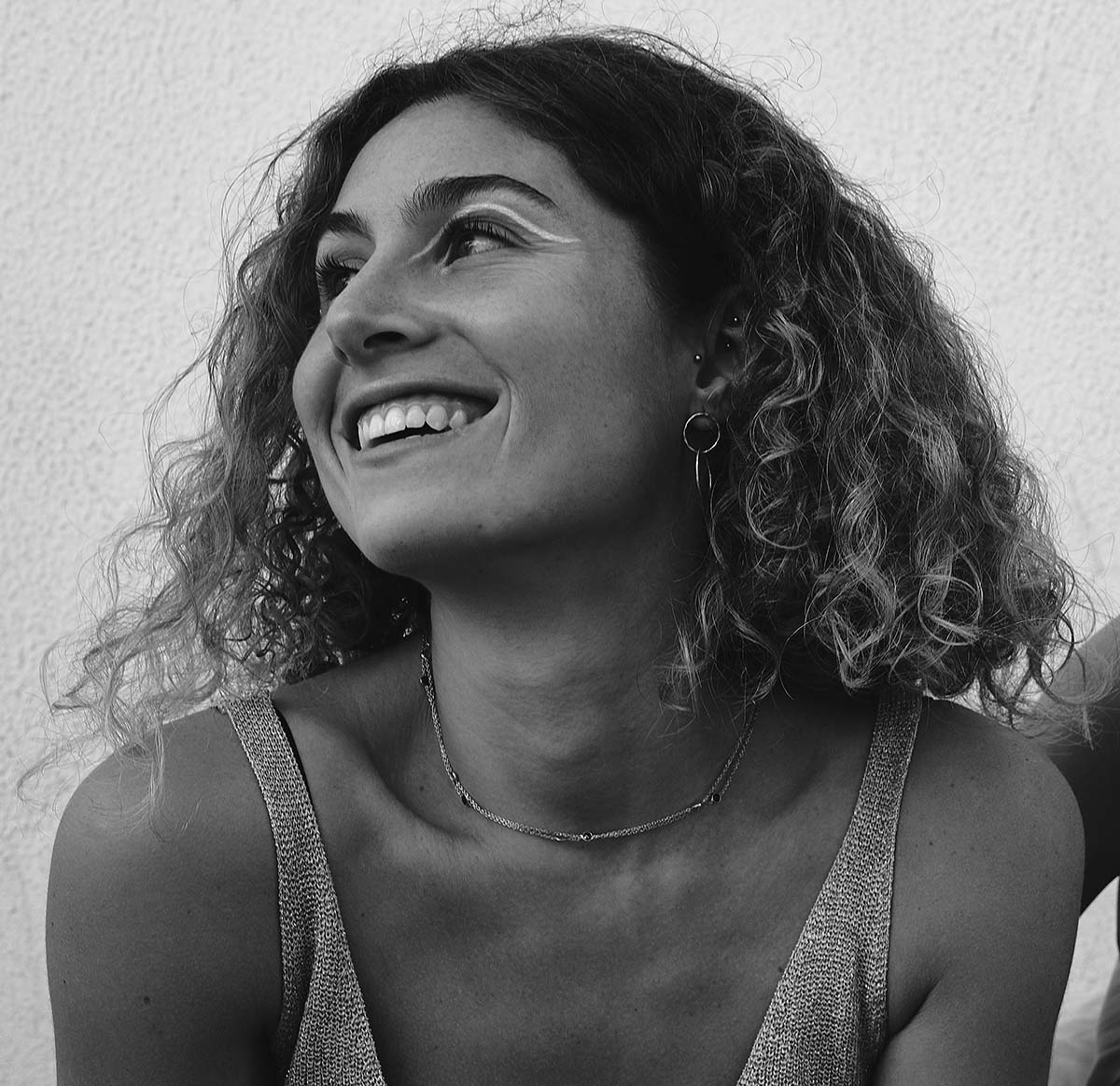 Mujer sonriente en blanco y negro usando el collar Casiopea bañado en oro de 18k con piedras semipreciosas de Isla Vurma