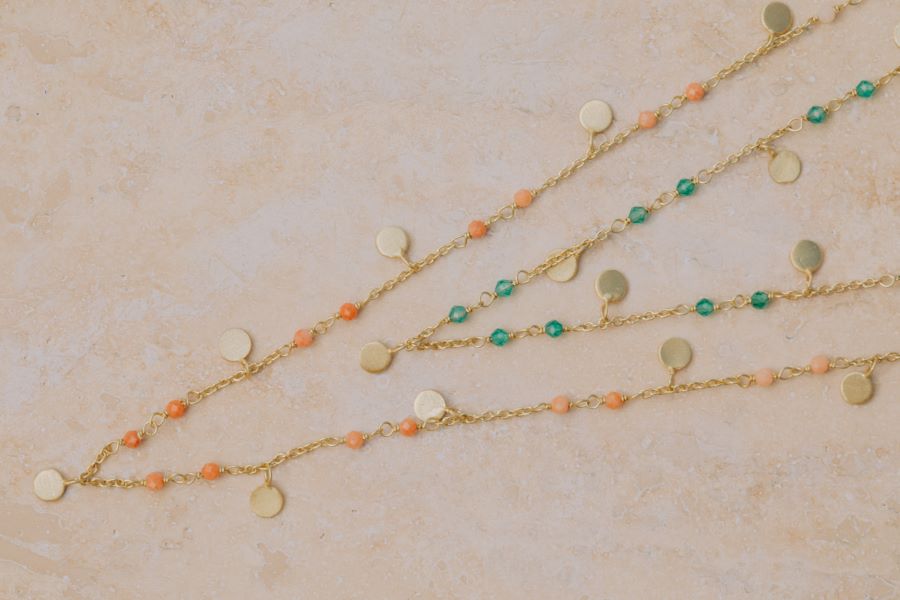 Primer plano del conjunto de collares bañados en oro, compuesto por piedras Jade, Piedra de Luna Melocotón y pequeños discos dorados de Isla Vurma