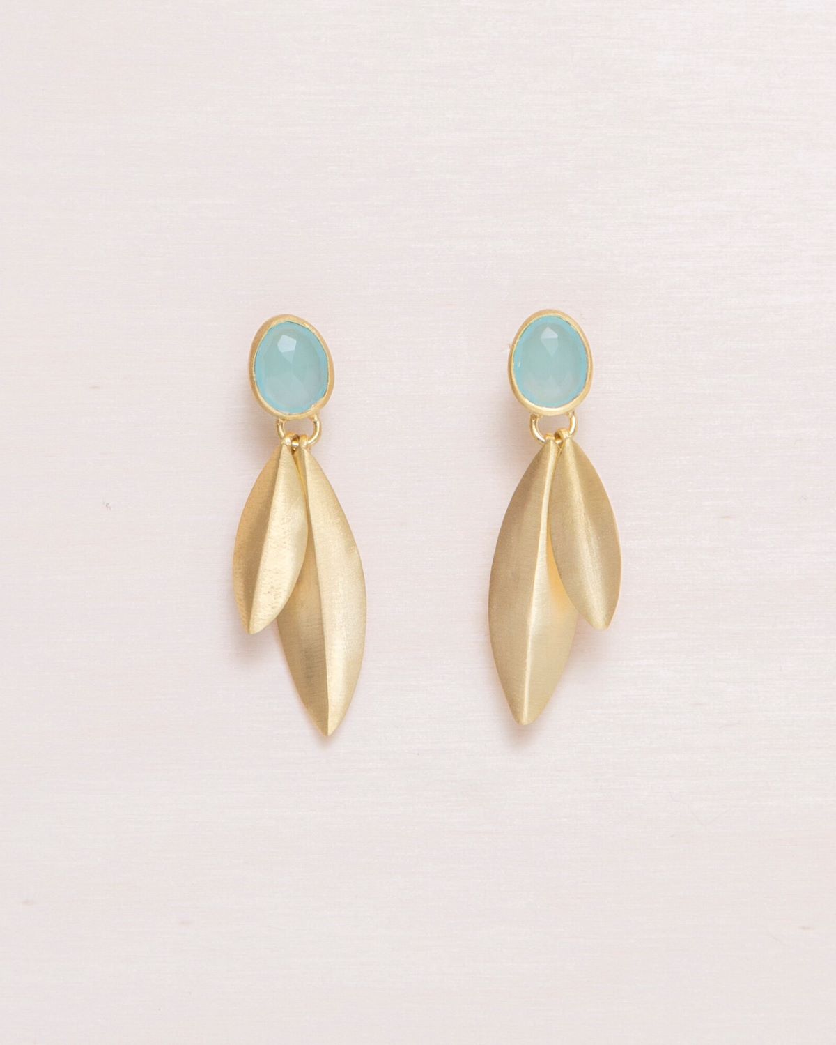 Pendientes dorados con cierre de botón y una piedra semipreciosa en Aqua Calcedonia en la parte superior, de cada piedra caen dos piezas metálicas alargadas con forma de hoja, también en acabado dorado