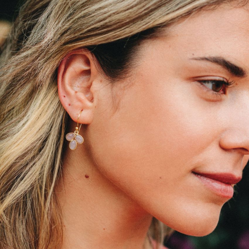Modelo con pendientes en forma de pétalo con piedra semipreciosa en Piedra Luna Melocotón incrustada y cierre de gancho abierto de Isla Vurma