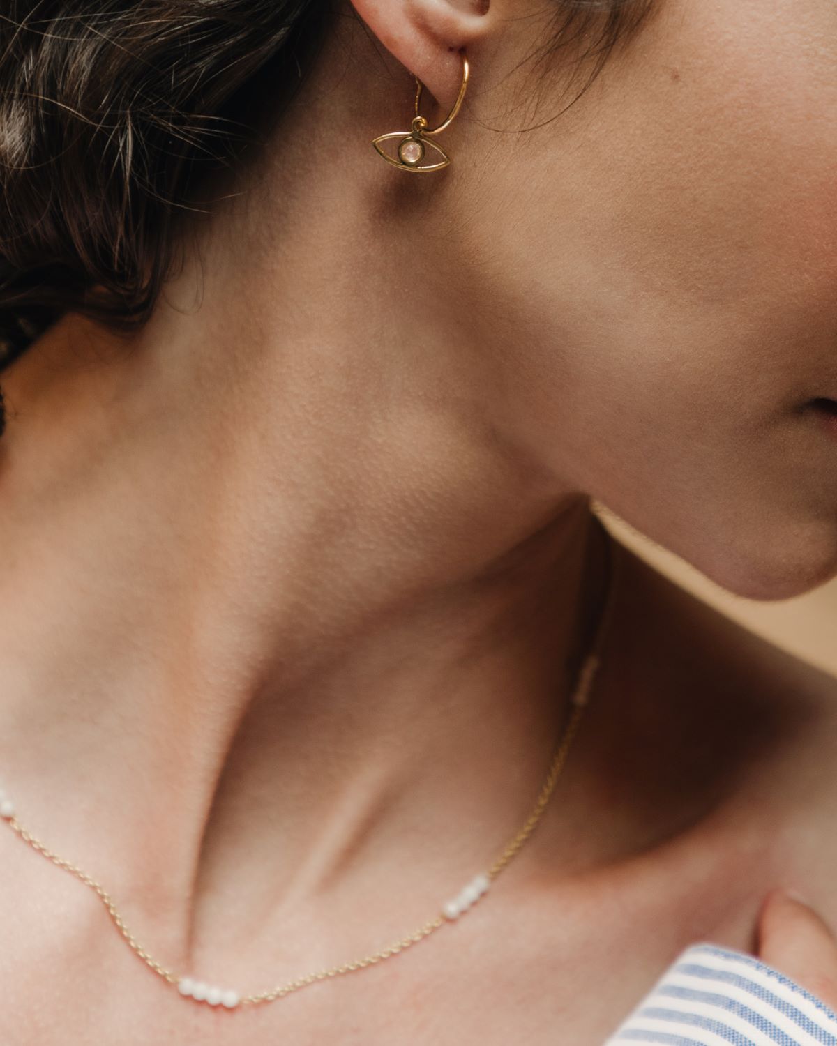 Modelo con pendientes y collar bañado en oro de 18 quilates compuesto por pequeñas tiras de piedras semipreciosas Piedra de Luna de Isla Vurma