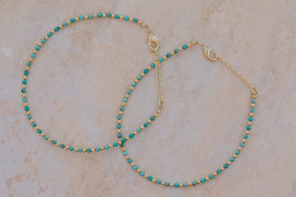 Primer plano de un conjunto de dos pulseras con cuentas facetadas de piedra semipreciosa en Aqua Calcedonia y bañadas en Oro de 18 quilates con cierre de gancho bañado en oro de 18 quilates