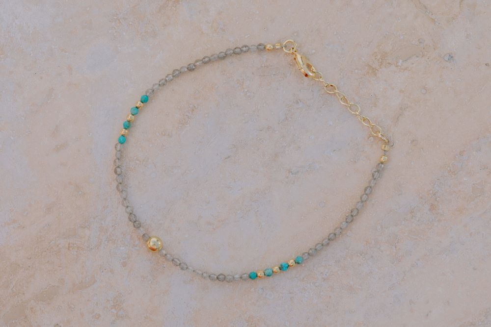 Primer plano una pulsera con cuentas facetadas de piedra semipreciosa en Labradorita, Aqua Calcedonia y bañadas en Oro de 18 quilates