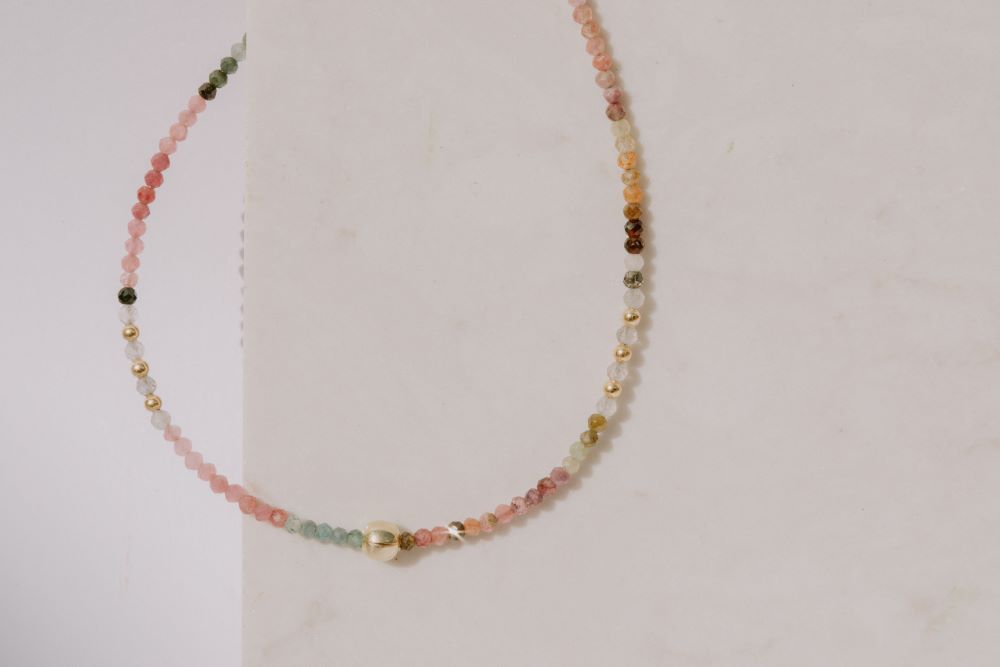 Primer plano de un conjunto compuesto por dos pulseras con cuentas facetadas de piedra semipreciosa en Turmalina Multicolor y bañadas en Oro de 18 quilates con cierre de gancho