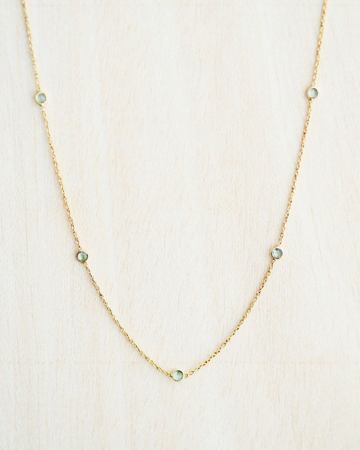 Collar bañado en oro de 18k con piedras de Aqua Calcedonia sobre fondo claro de Isla Vurma