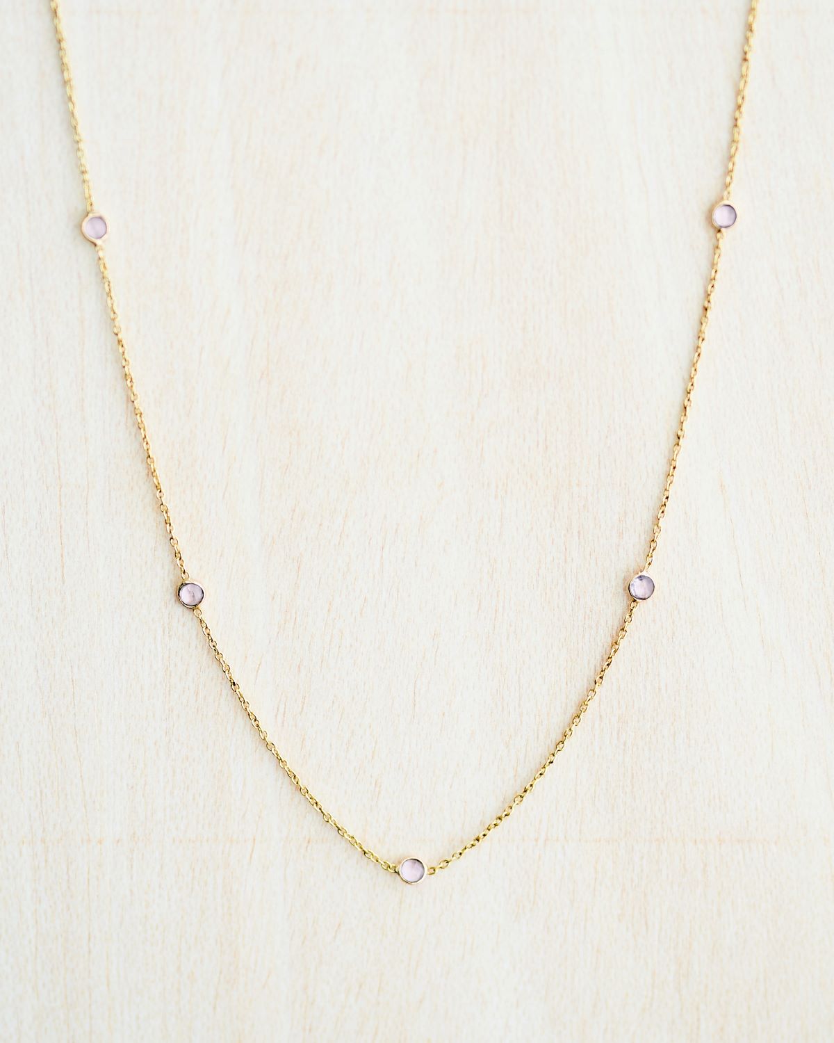 Collar bañado en oro de 18k con piedras de Cuarzo Rosa sobre fondo claro de Isla Vurma