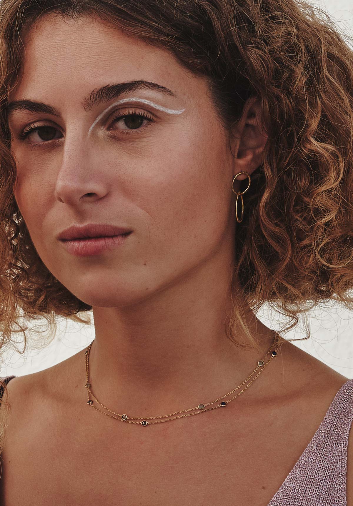 Mujer con cabello rizado lleva el collar con piedras semipreciosas de Lapislázuli, Cuarzo Rosa, Aqua Calcedonia, Amatista Verde y cadena dorada de Isla Vurma