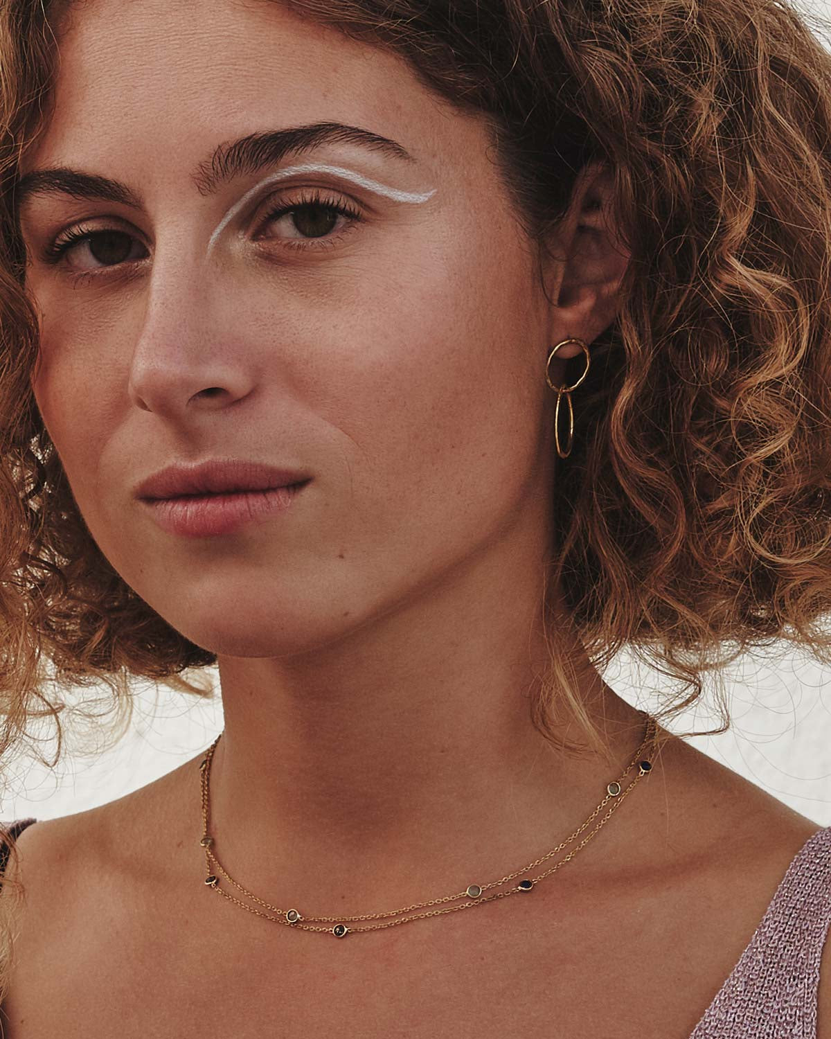 Mujer con cabello rizado lleva el collar con piedras semipreciosas de Lapislázuli, Cuarzo Rosa, Aqua Calcedonia, Amatista Verde y cadena dorada de Isla Vurma