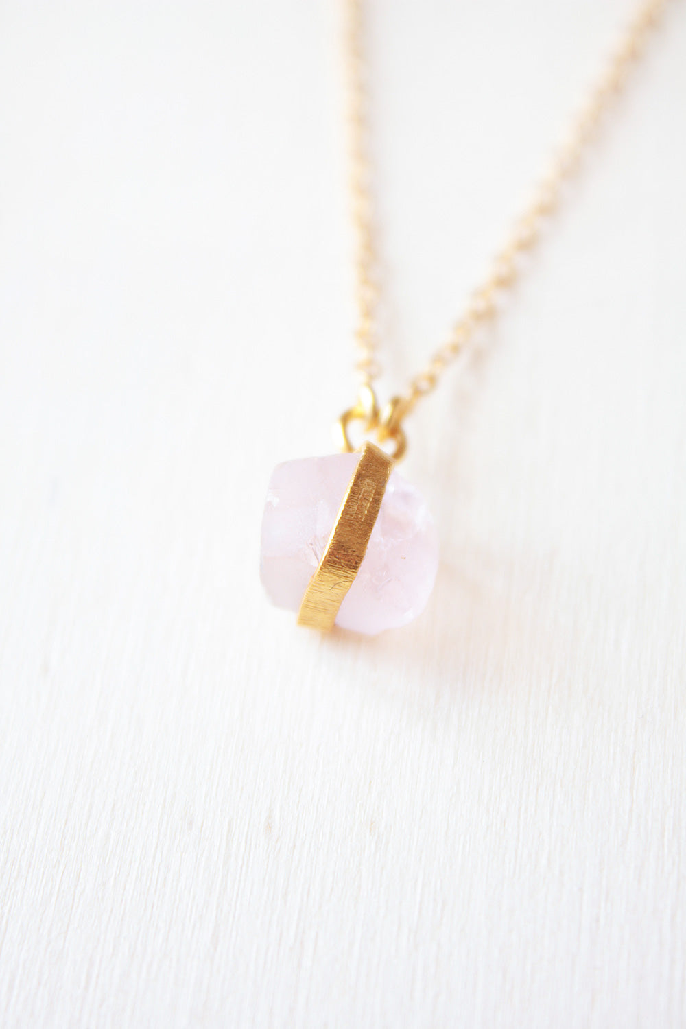 Primer plano de la piedra semipreciosa de Cuarzo Rosa sujeta por una pequeña pieza dorada de Isla Vurma