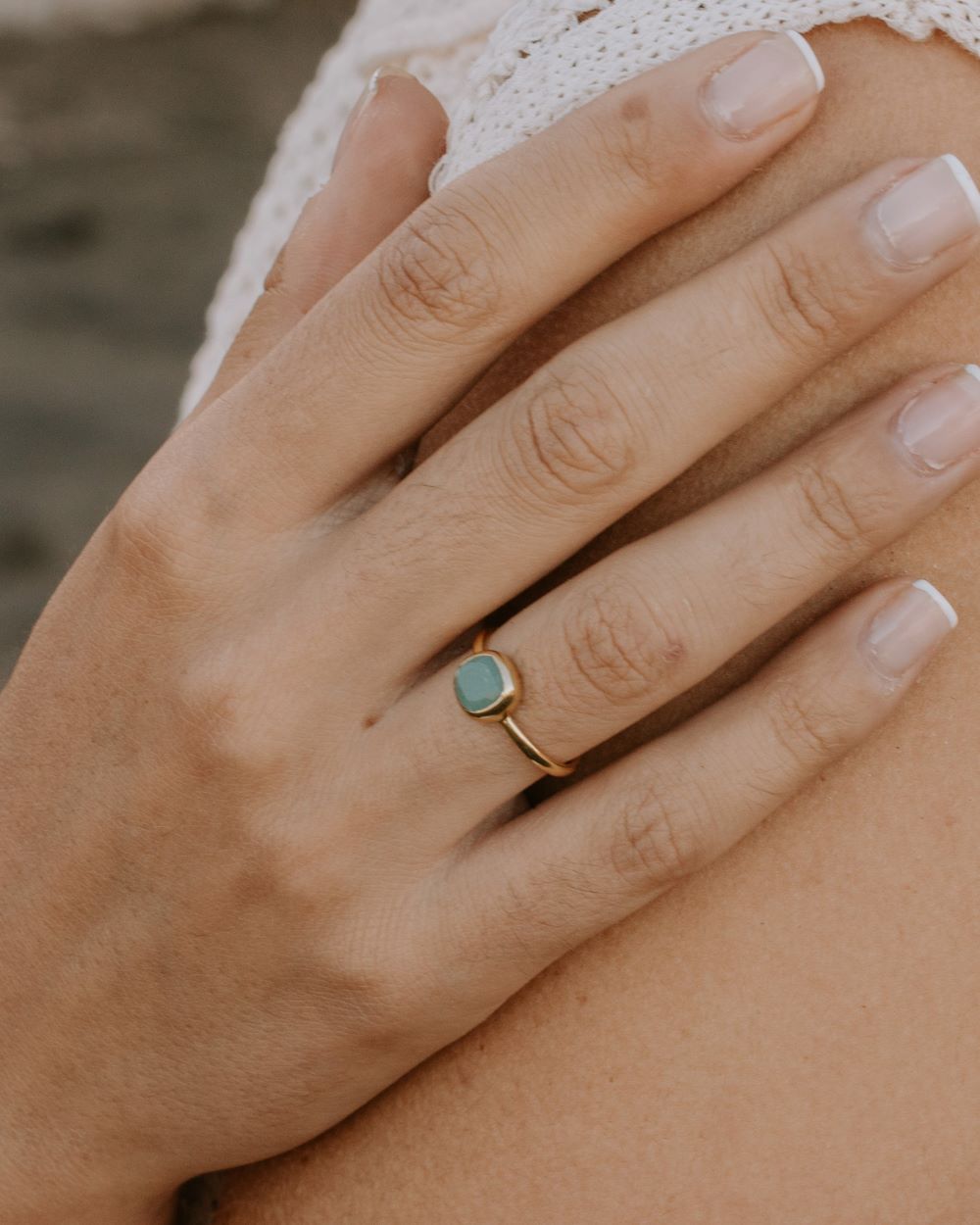 Mano de la modelo con el anillo bañado en oro con piedra central cuadrada en Aventurina Verde