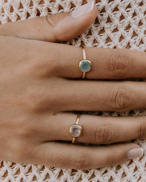 Mano de la modelo con el anillo bañado en oro con piedra central cuadrada en Aventurina Verde y Cuarzo Rosa