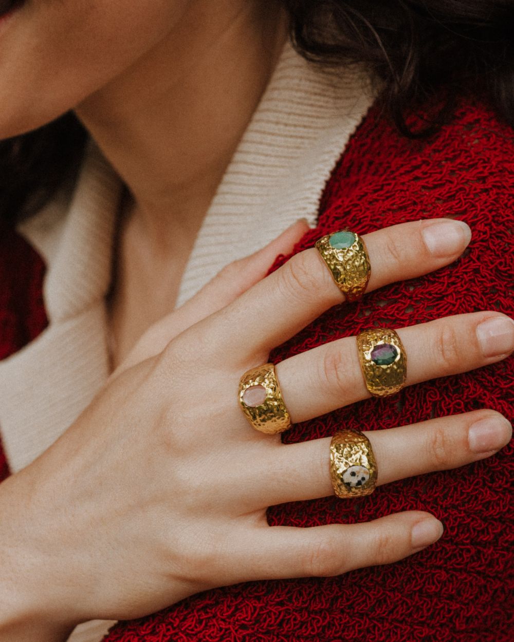 Primer plano de la mano de la modelo con los anillos bañados en oro de 18k con piedras semipreciosas Rubí Zoisita, Jaspe Dálmata, Cuarzo Melocotón y Aventurina Verde de Isla Vurma