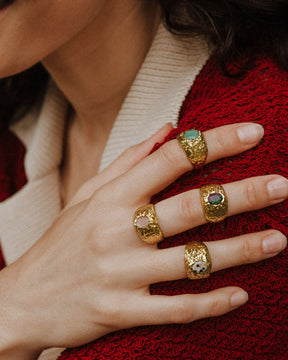 Primer plano de la mano de la modelo con los anillos bañados en oro de 18k con piedras semipreciosas Rubí Zoisita, Jaspe Dálmata, Cuarzo Melocotón y Aventurina Verde de Isla Vurma