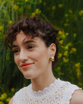 Modelo con los pendientes bañados en oro de 18 quilates abiertos y cierre mariposa de Isla Vurma