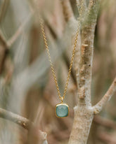 Collar con pieza cuadrada disponible en Aqua Calcedonia, en un fondo natural de Isla Vurma