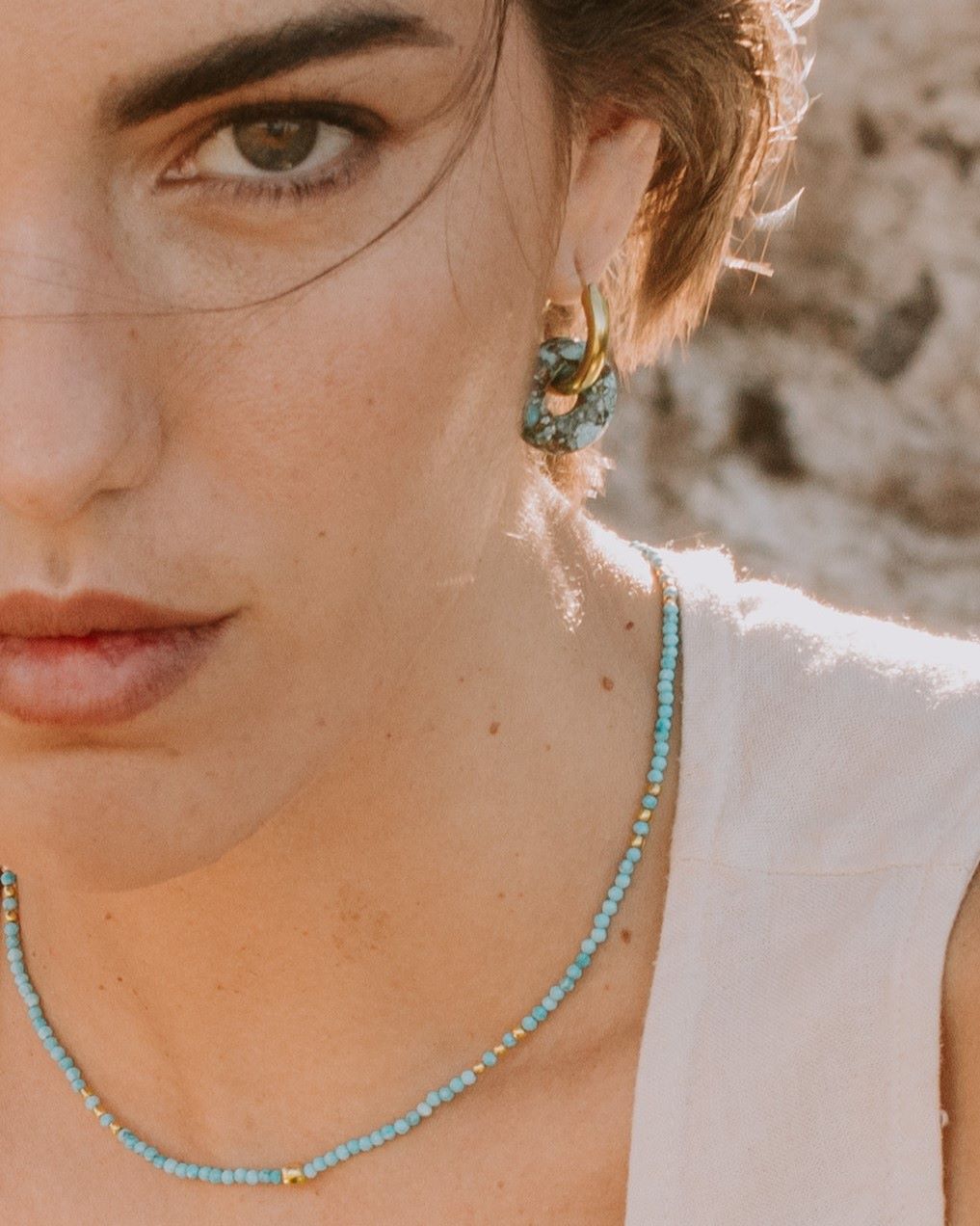 Modelo con pendientes turquesas y collar en tonos azules claros