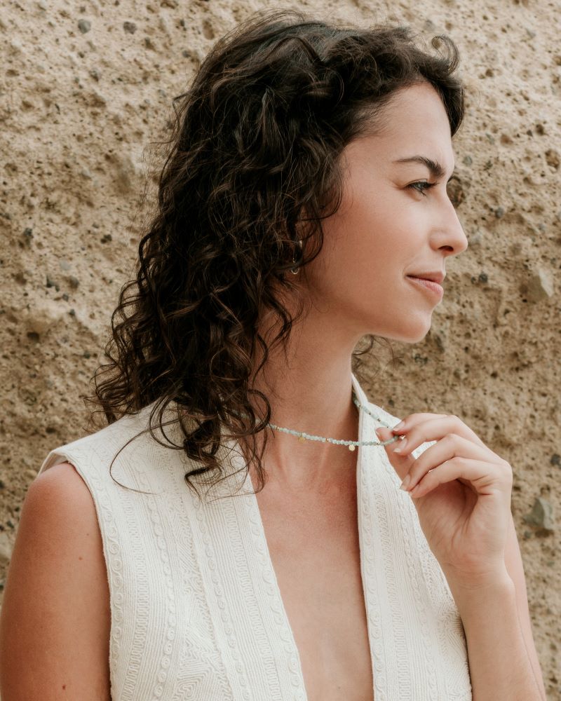 Medio plano de modelo sujetando el collar en piedra semipreciosa de Aqua Calcedonia de Isla Vurma