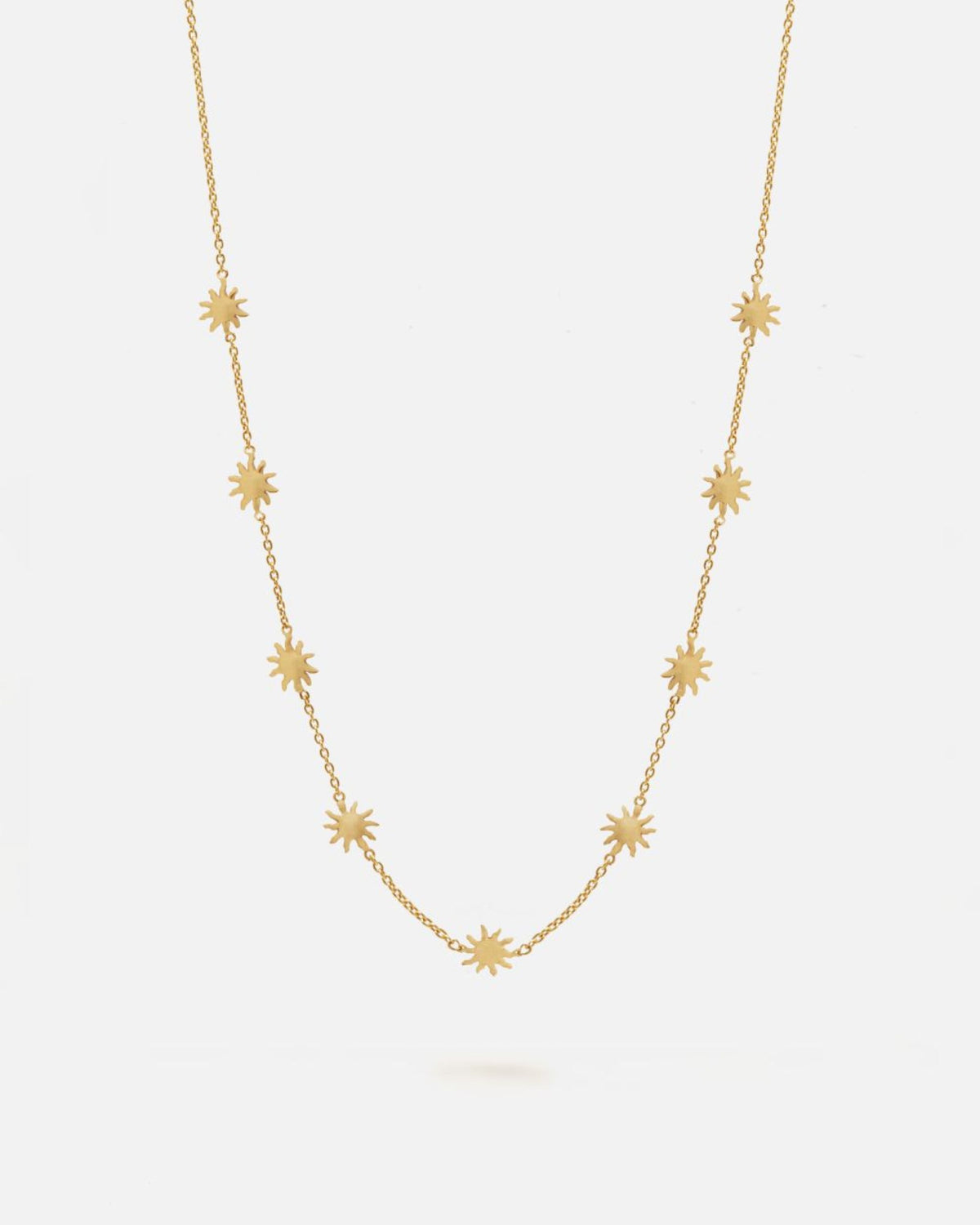 Collar dorado de cadena fina decorado con pequeños colgantes en forma de estrella de ocho puntas distribuidos de manera uniforme