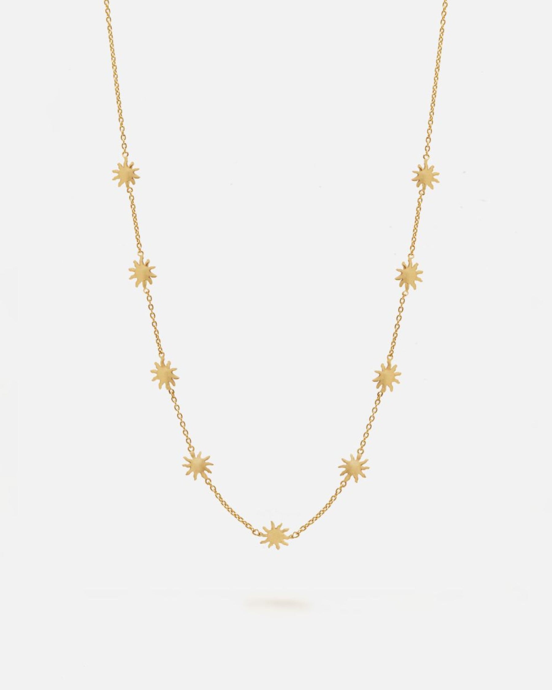 Collar dorado de cadena fina decorado con pequeños colgantes en forma de estrella de ocho puntas distribuidos de manera uniforme