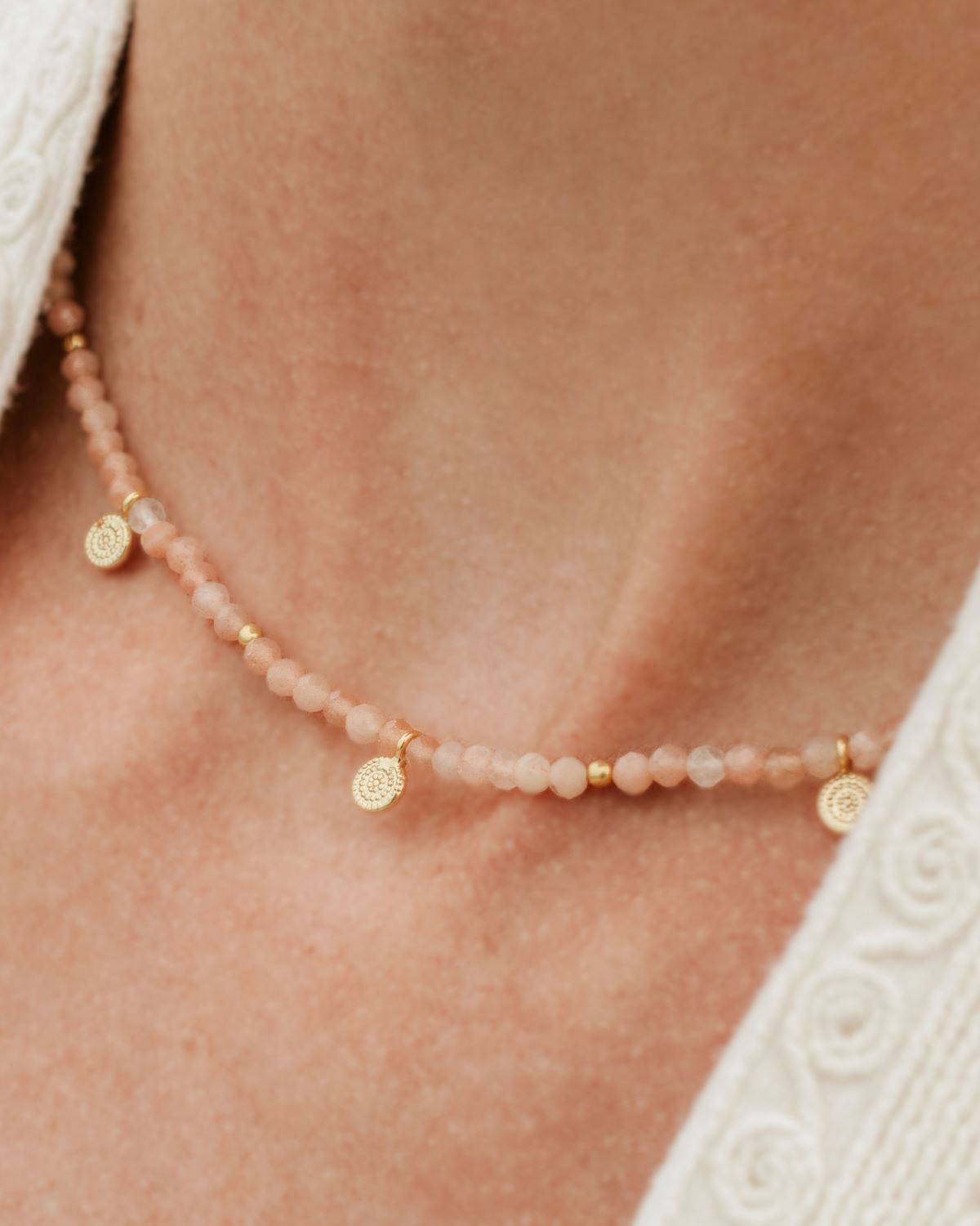 Primer plano del cuello de la modelo con collar bañado en oro de 18 quilates junto a piedras semipreciosas en Piedra de Luna Melocotón de Isla Vurma