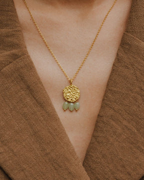 Primer plano del cuello de la modelo llevando el collar bañado en oro de 18 quilates con una pieza circular martillado con tres piedras semipreciosas en forma de gota en Aventurina Verde de Isla Vurma