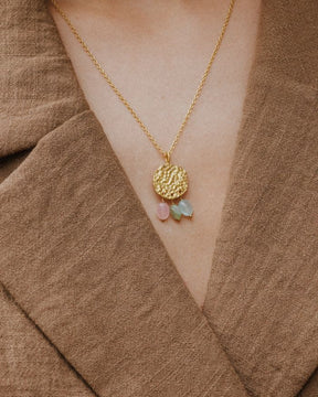 Primer plano del cuello de la modelo llevando el collar bañado en oro de 18 quilates con una pieza circular martillado con tres piedras semipreciosas en forma de gota en Aventurina Verde, Aqua Calcedonia y Cuarzo Melocotón de Isla Vurma