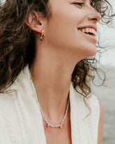 Modelo con conjunto de collar en piedra semipreciosa Aqua Calcedonia y aro dorado en piedra semipreciosa Jade de Isla Vurma