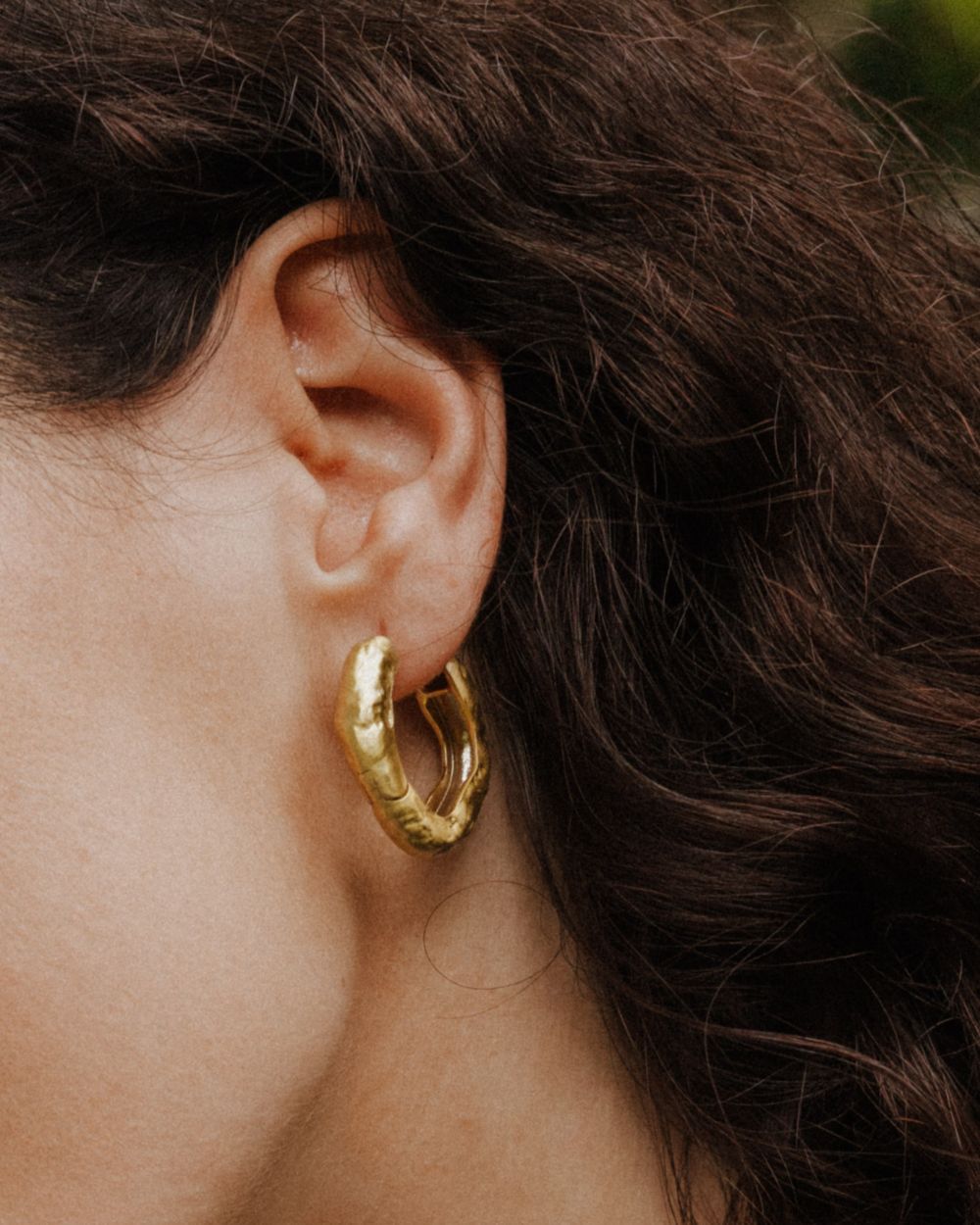 Primer plano de la modelo llevando los pendientes gruesos circulares irregulares bañados en oro de 18k de Isla Vurma