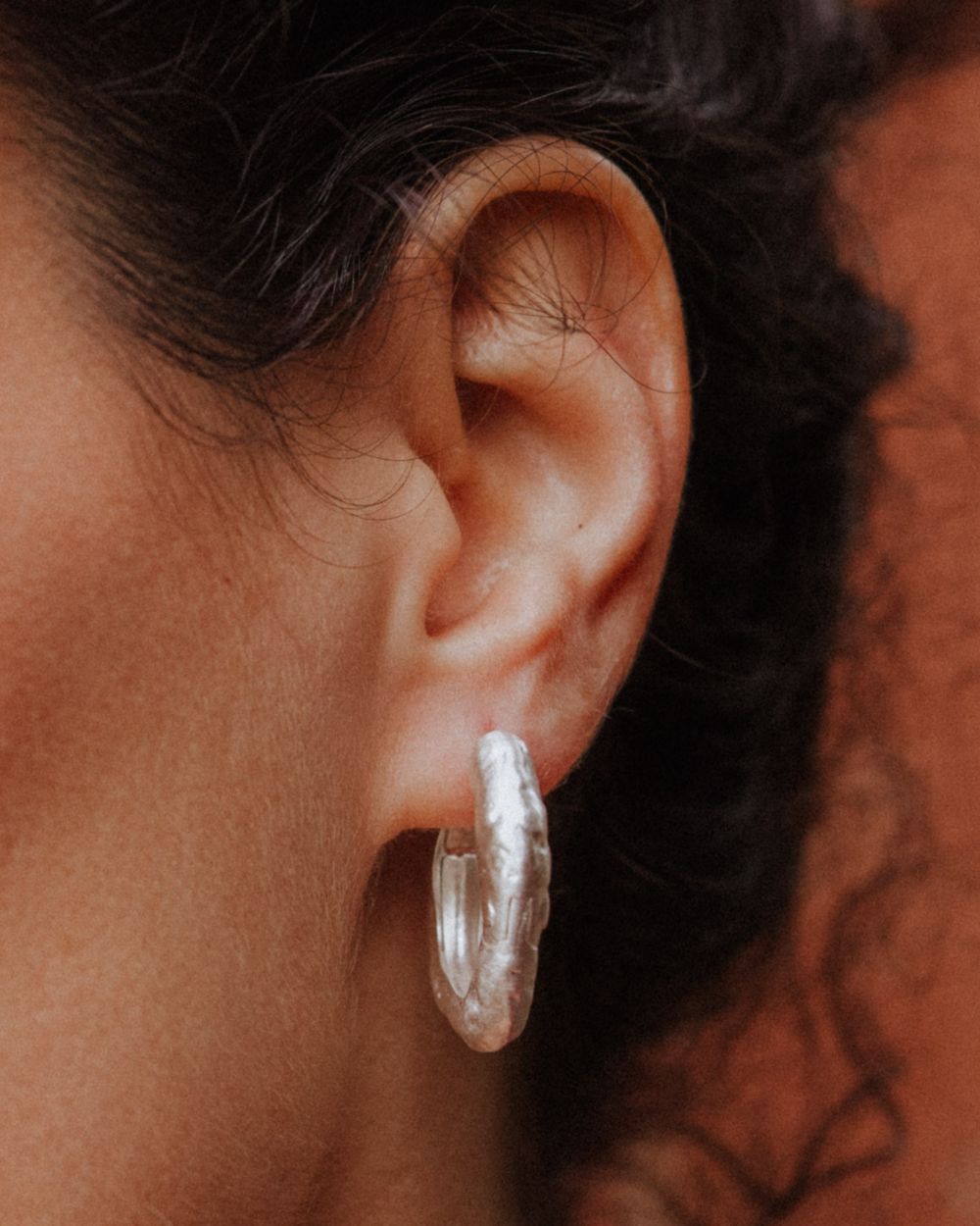 Primer plano de la modelo llevando los pendientes gruesos circulares irregulares bañados en plata 925 de Isla Vurma